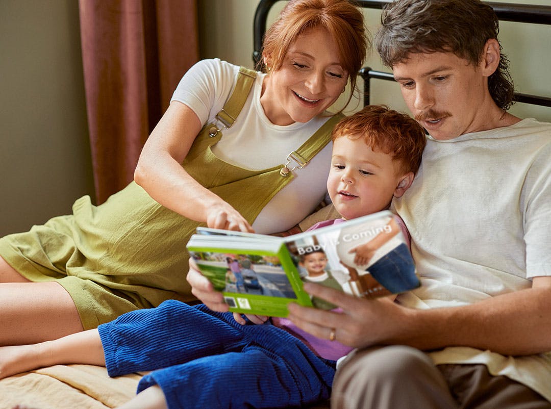 Family reading the Baby is Coming board book by Lovevery