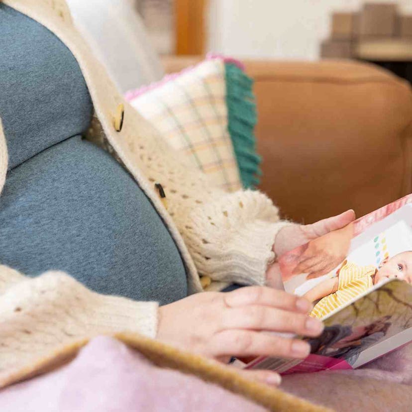 Pregnant mother looking at a book from Lovevery