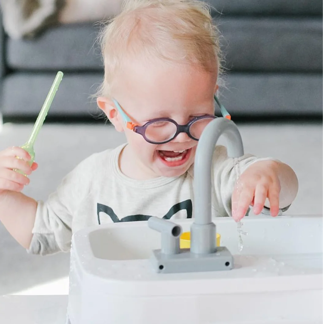 Child happily playing with the Super Sustainable Sink from The Helper Play Kit