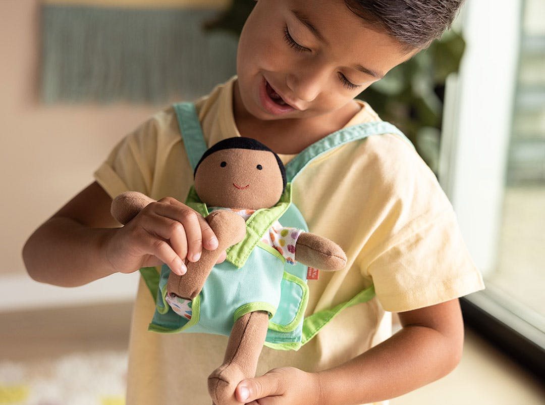 Boy wearing accessories with the Lovevery Baby Doll from The New Sibling Course
