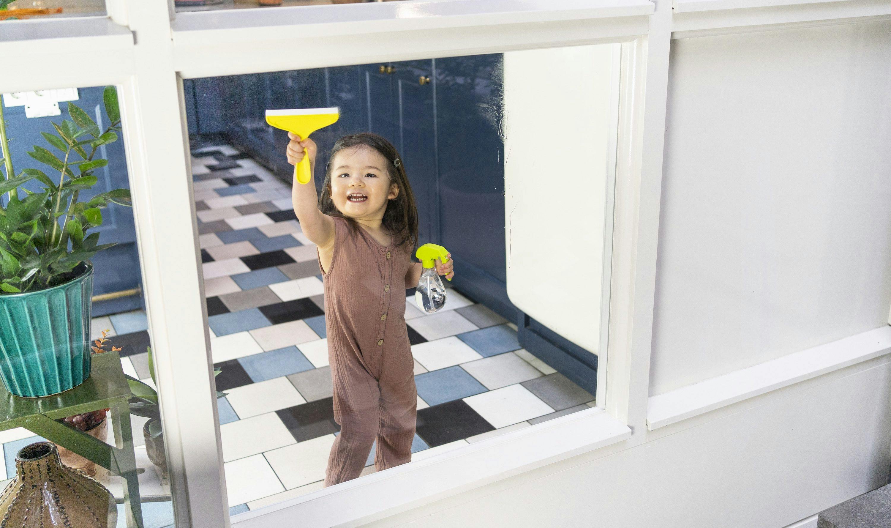 Child using the Squeaky Clean Squeegee Set on a window